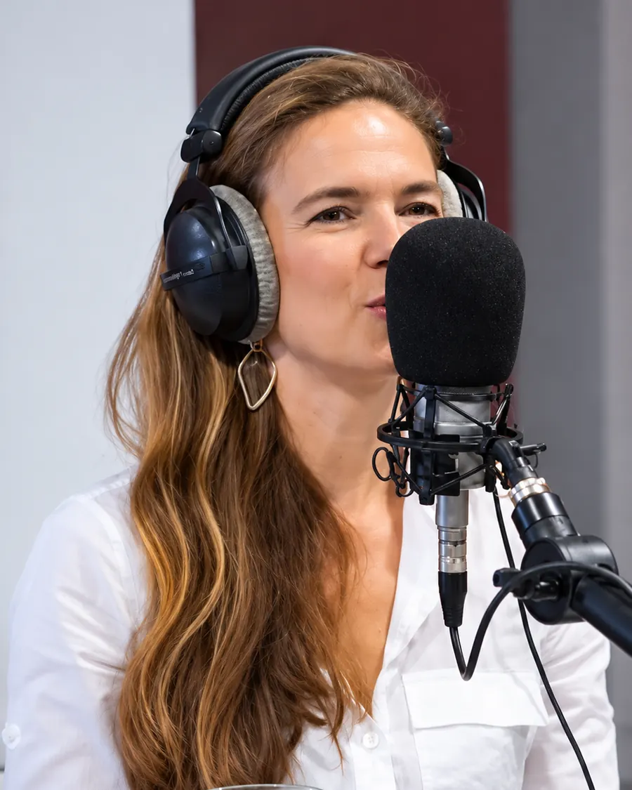 Simona Nicolaescu în studio, cu căștile pe urechi, vorbind la microfon.